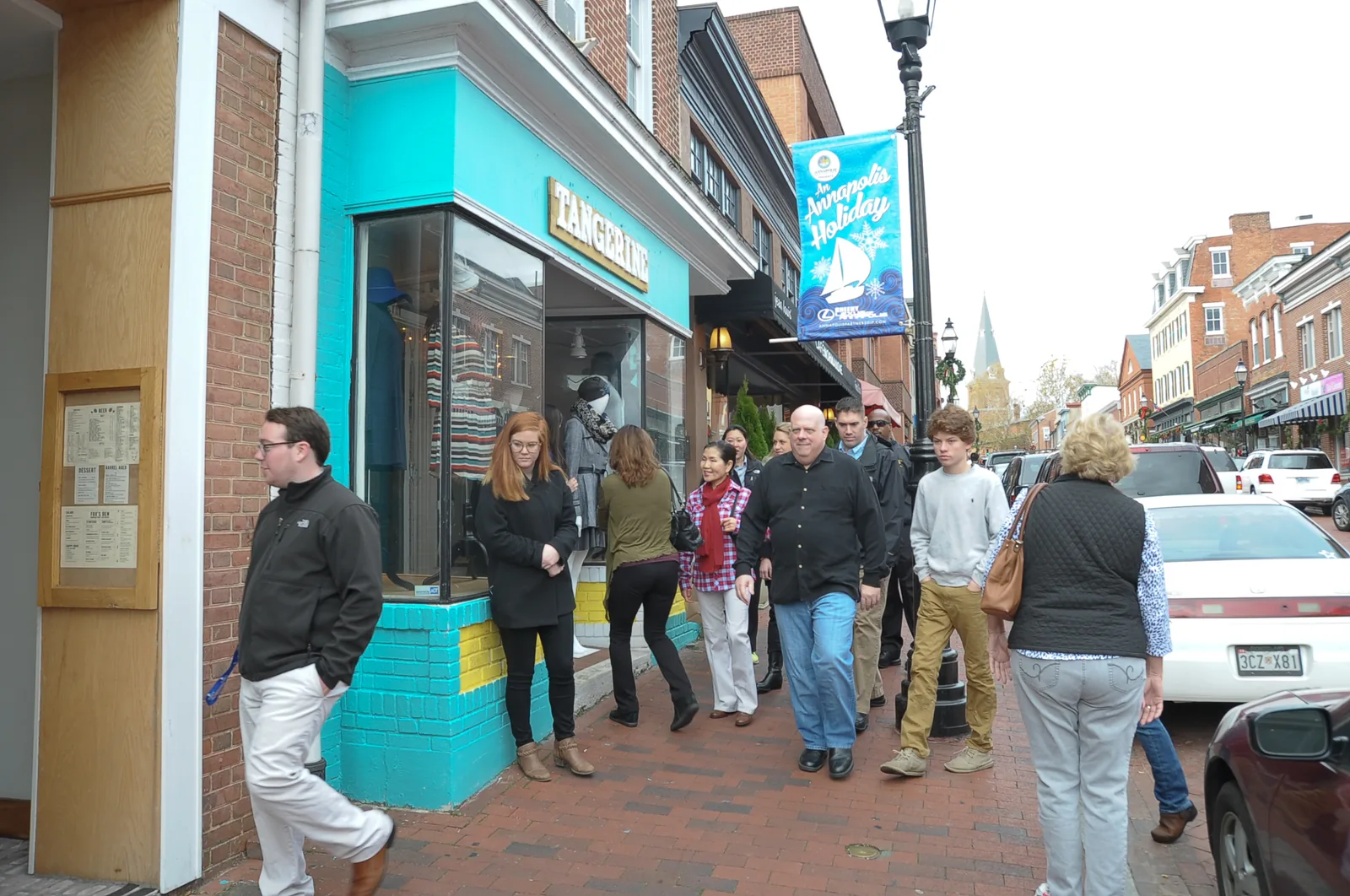Shoppers walk past small storefronts on a brick sidewalk on Small Business Saturday
