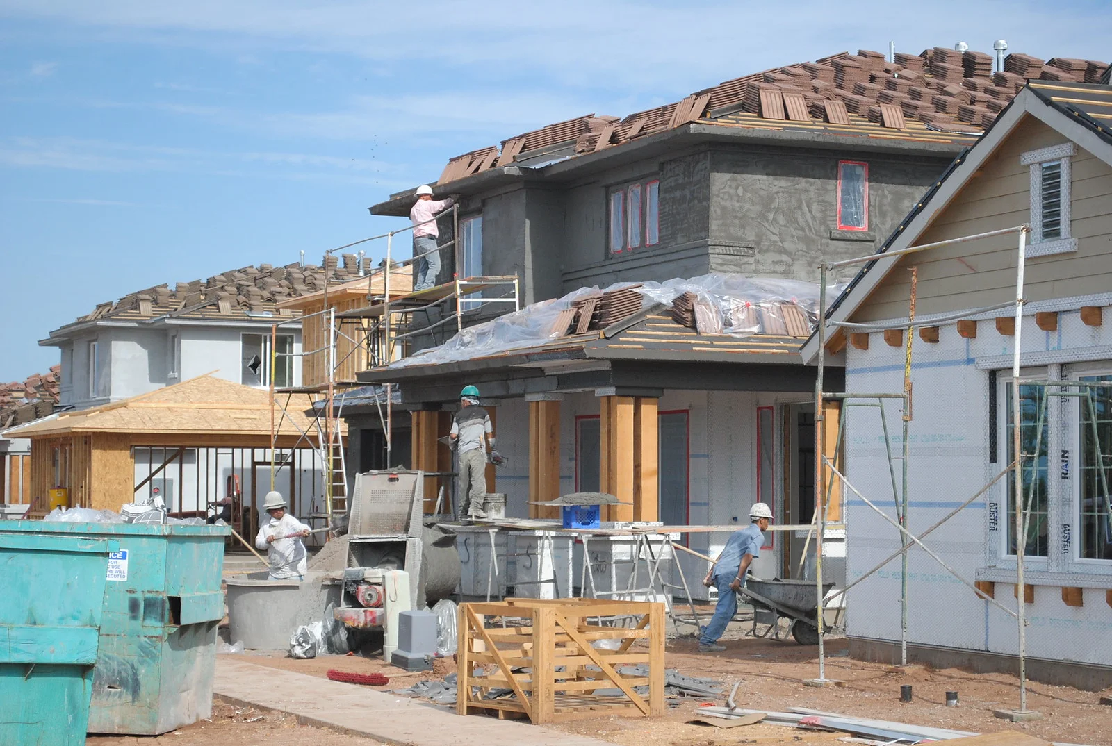Crews finish stucco, roofing and siding on new two-story homes in a subdivision in Gilbert, Arizona