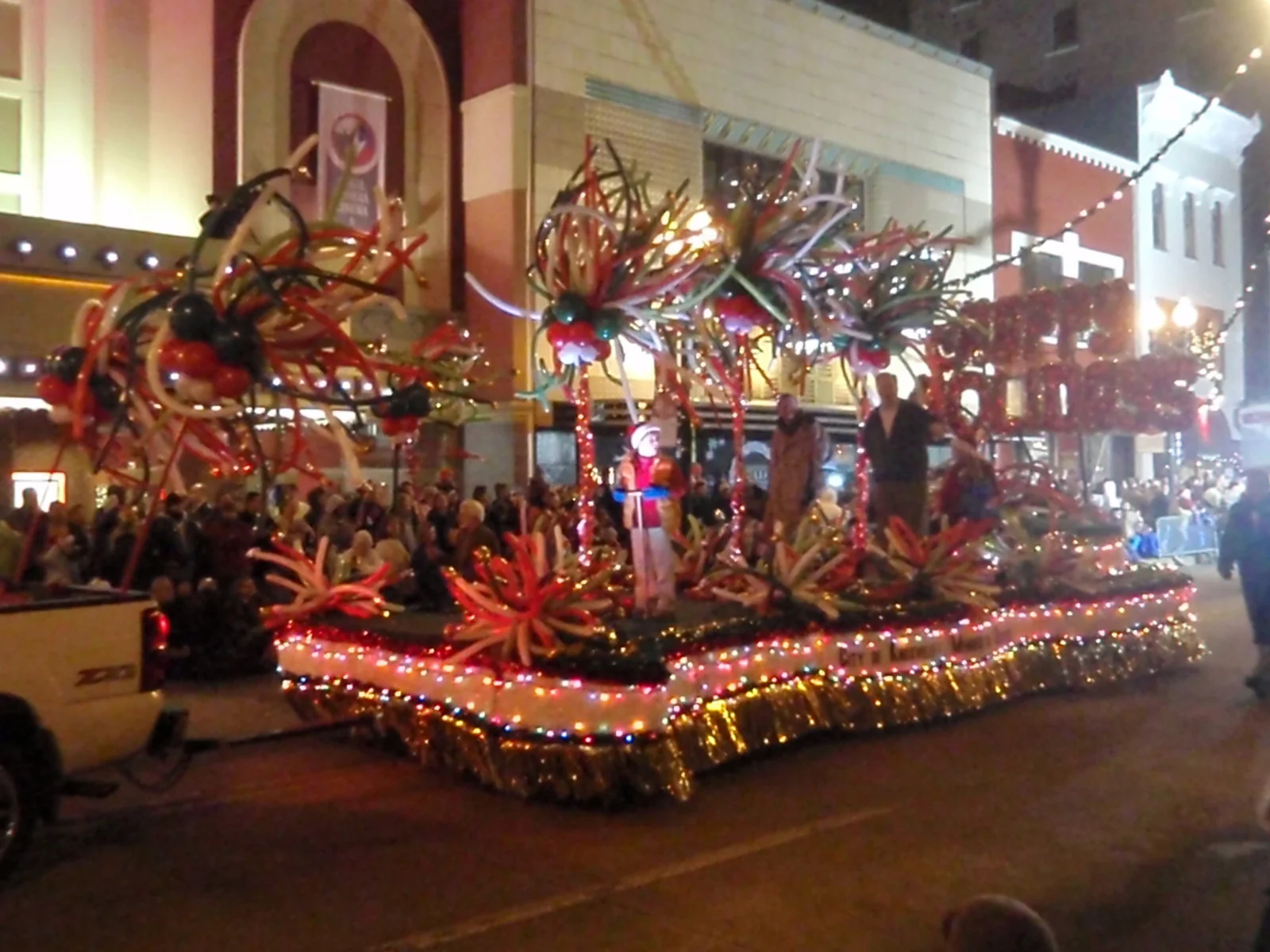 A float trimmed with Christmas lights and balloon sculptures in a nighttime Christmas parade on Gay Street in Knoxville