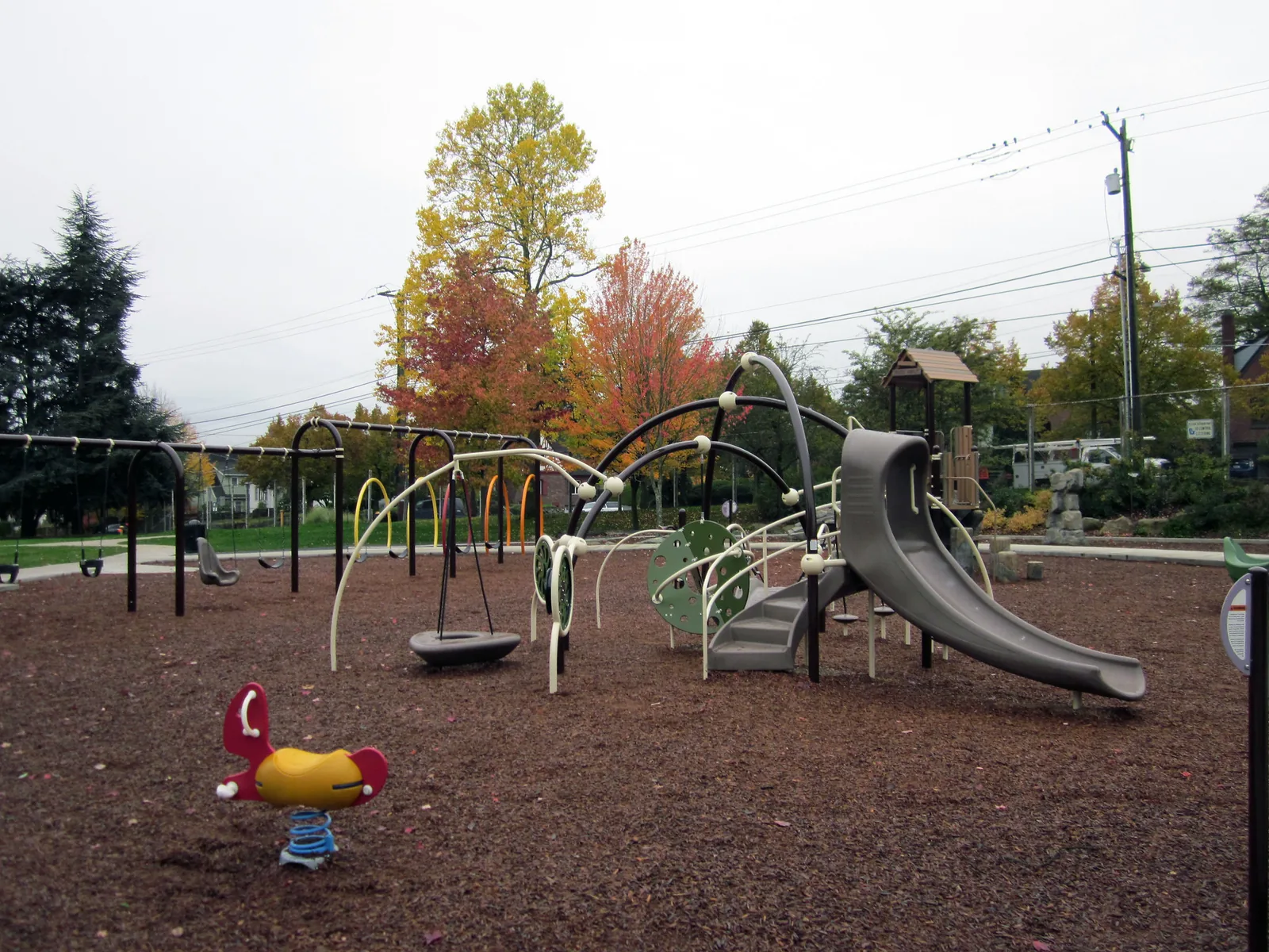 Slides, climbing bars and a spring rider on a wood-chip playground in a park in Seattle