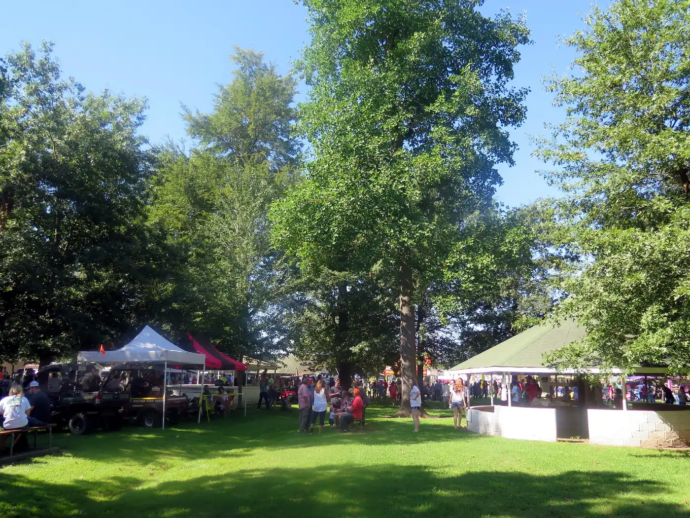 Families gather under tents and trees on a lawn at a Labor Day picnic
