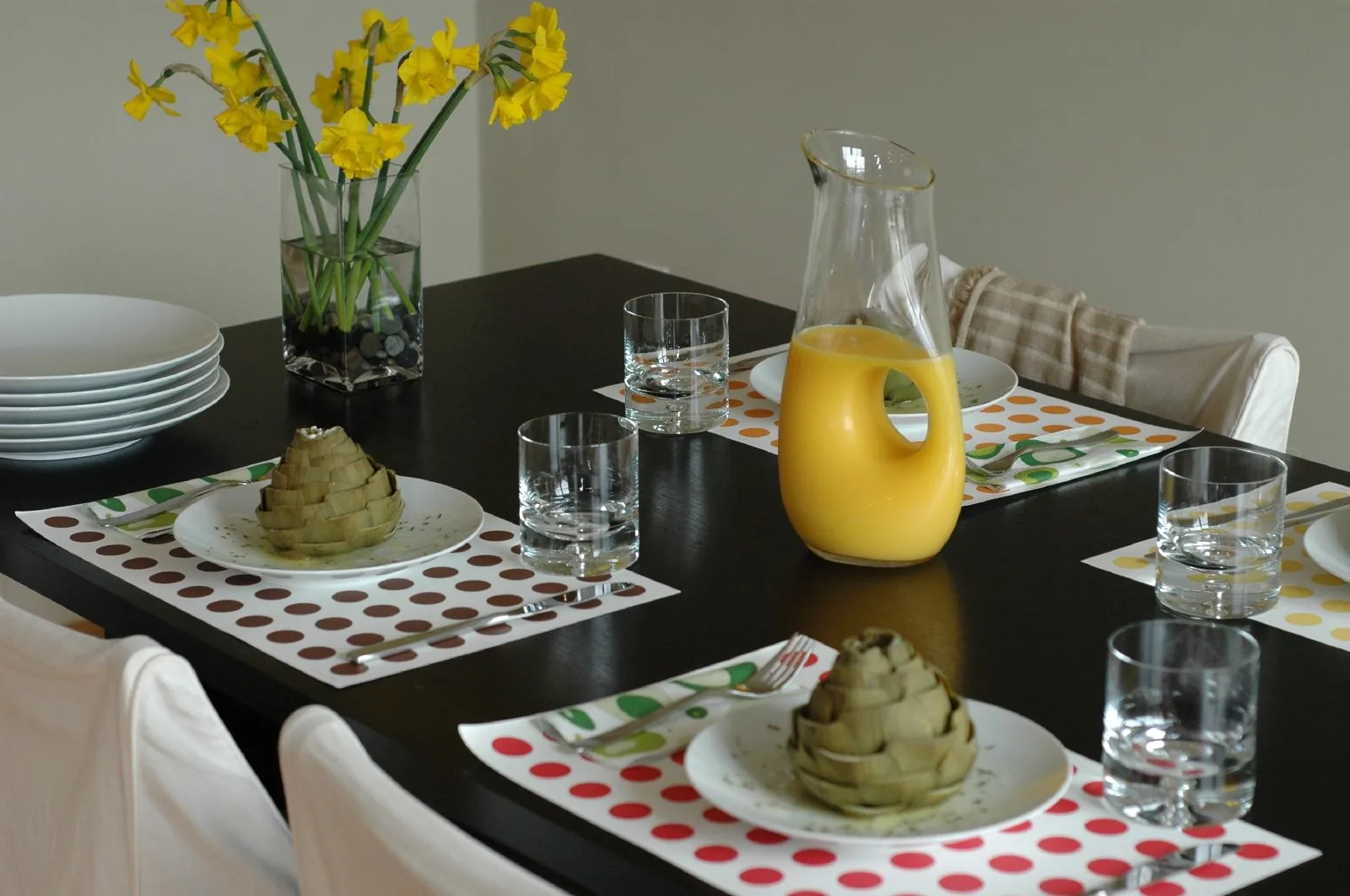 A table set for brunch with daffodils, orange juice and artichokes on polka-dot place mats